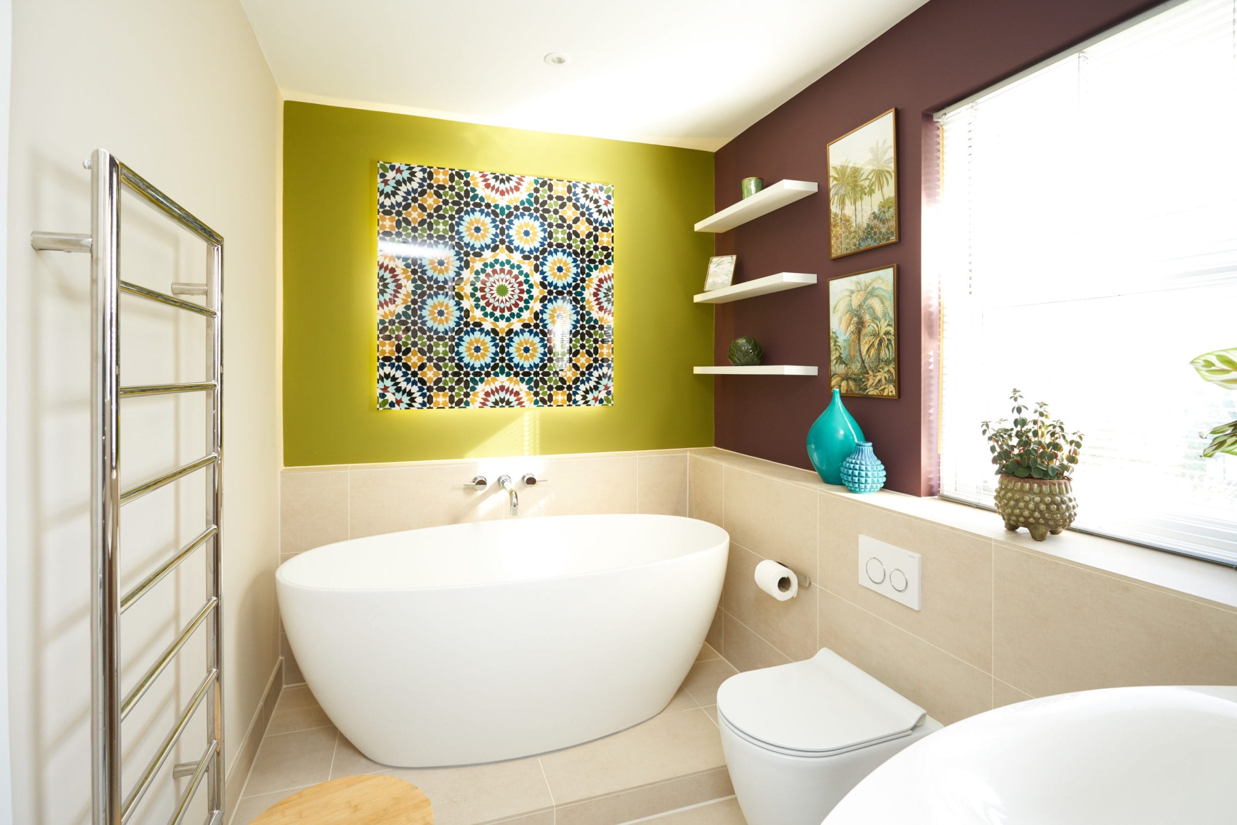 A modern bathroom featuring a freestanding tub, vibrant wall colours, and decorative shelves.