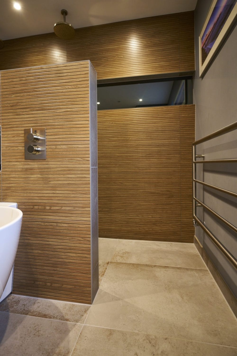 Modern brushed nickel shower controls and wood-effect tile wall, combining organic textures with sleek finishes