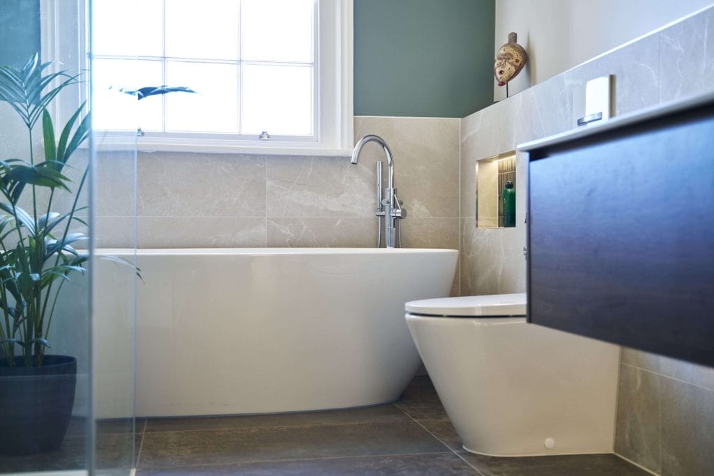 Minimalist bathroom with freestanding bathtub, wall niche, and modern fixtures, accented by green walls.