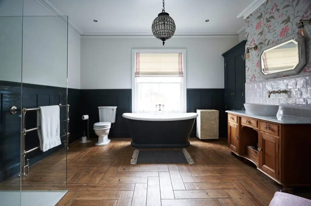 large bathroom with herringbone flooring and dark grey wood panelling