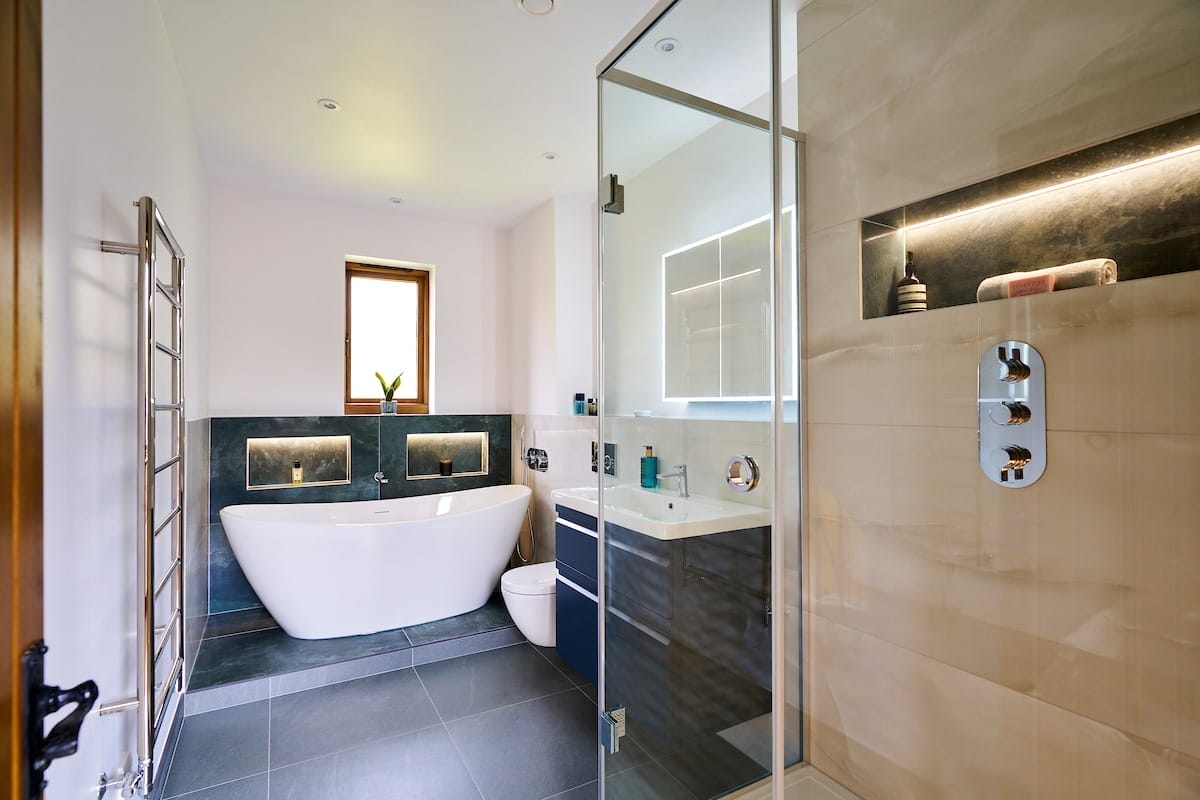 luxury modern bathroom design featuring freestanding bath and large grey tiles