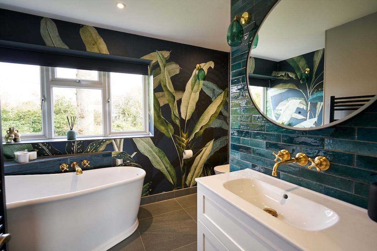 Luxury en-suite with freestanding bath and tropical themed feature wall in Surrey