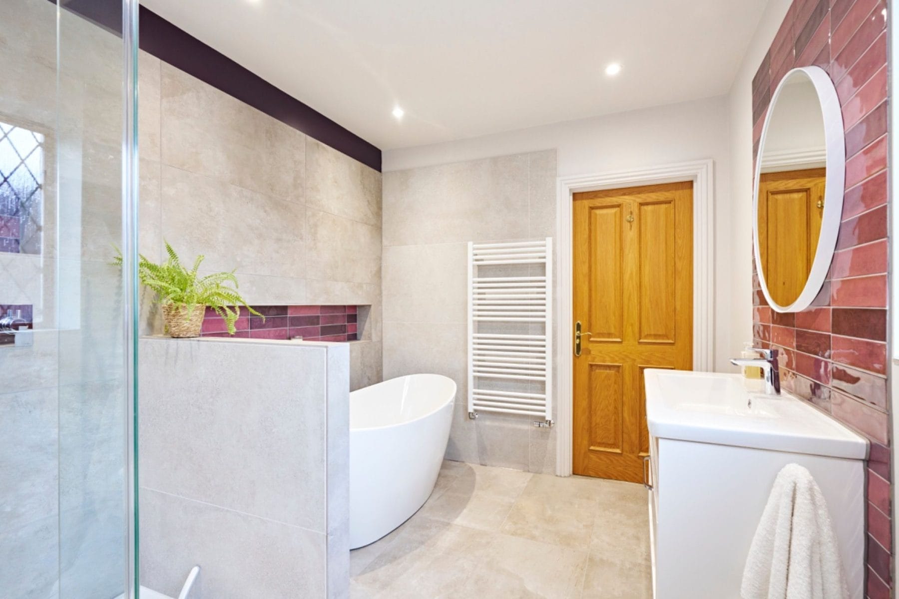 Freestanding bath with recessed purple tile niches in a modern Sussex en-suite
