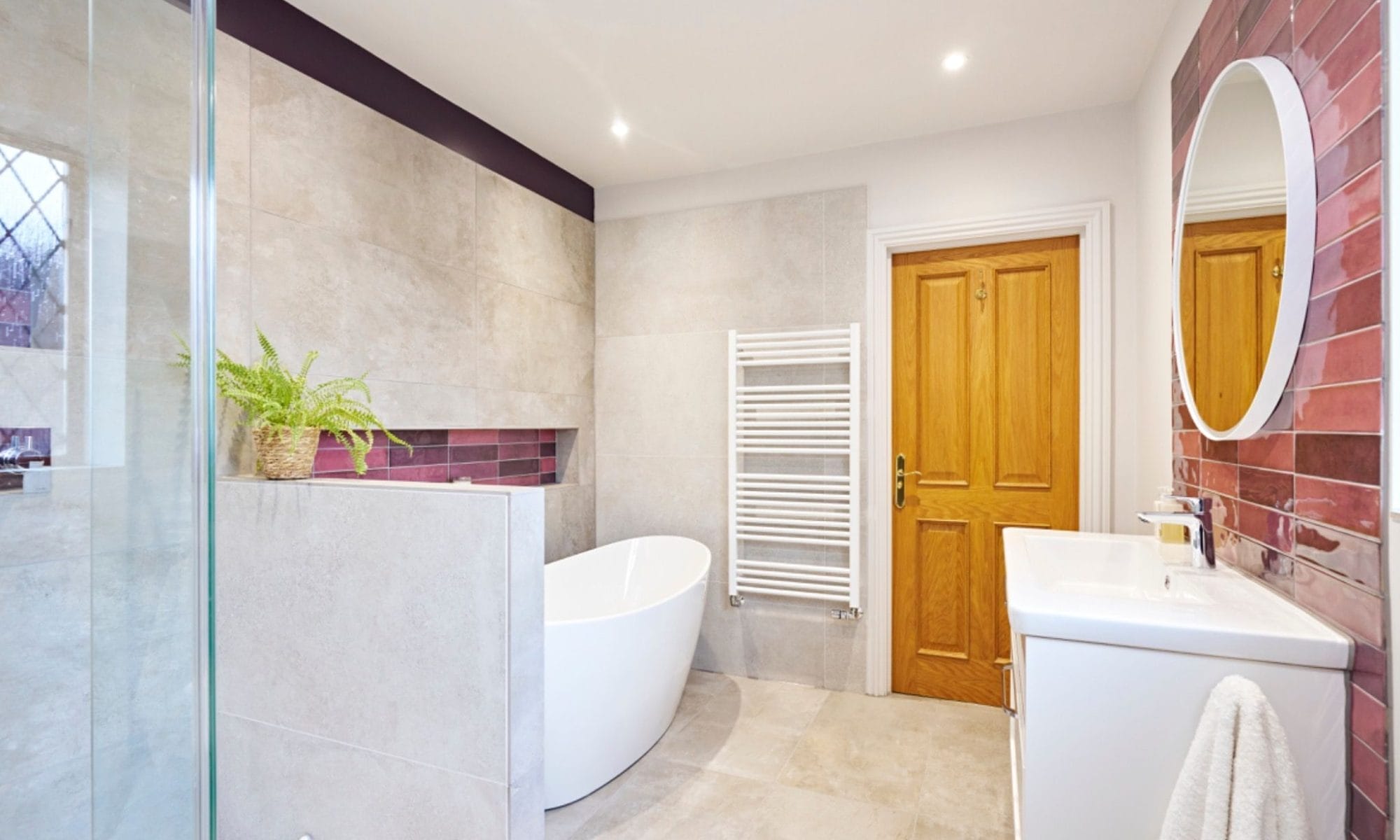 Freestanding bath with recessed purple tile niches in a modern Sussex en-suite