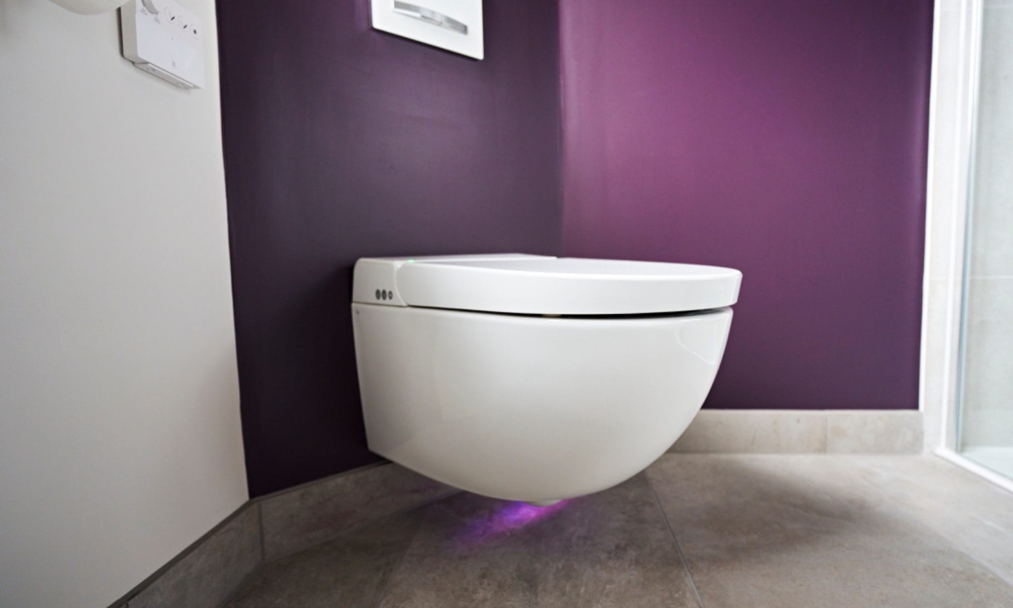 Modern wall-hung toilet with purple painted backdrop