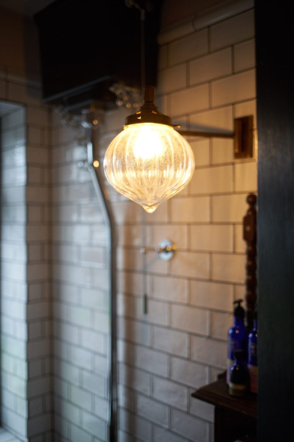 Bathroom wall light with warm glow against white subway tiles allowing a spa like sanctuary