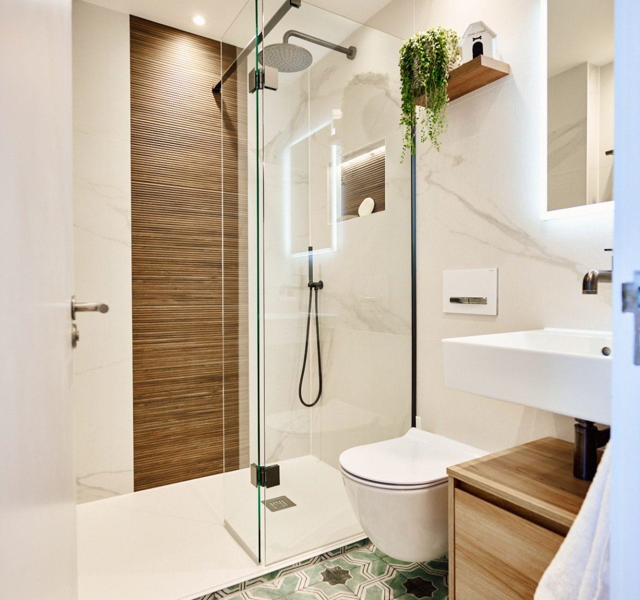 Compact luxury walk‑in shower room with ribbed wood feature wall, patterned floor tiles and wall‑hung vanity.